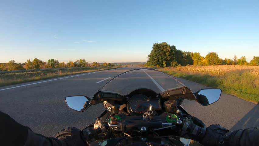 The viewpoint of motorcyclist driving motorbike at speed highway. Point of view of motorcycle rider rides fast in country road. Guy racing his motor bike during summer journey. Road trip concept. POV