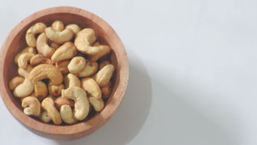cashew nuts in wooden bowl on white background