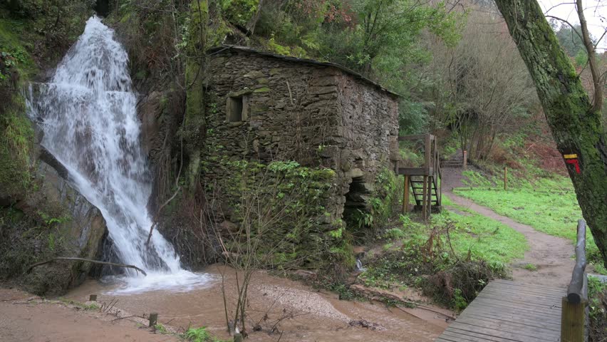 Water mill in the forest, next to a waterfall. Hiking trail.