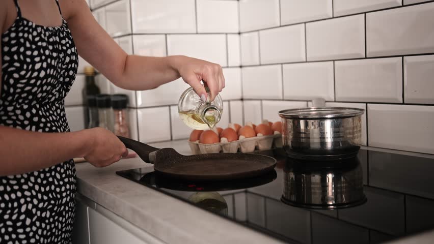 Girl Pouring Oil Into A Pan And Cooking Scrambled Eggs