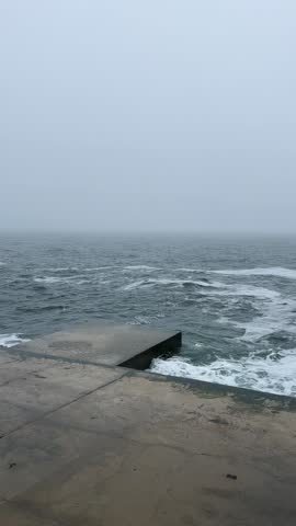 Fog Over Calm Sea: Soft Waves Against City Concrete. Dynamic shot