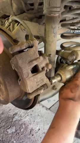 a man fixes a car in a garage, removes a wheel