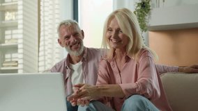 Mature senior middle aged Caucasian couple smiling cheerful woman man laugh together old family looking screen computer laptop pc talking at home sofa female male relaxing happy relationship good mood - Powered by Shutterstock - Get 15% off with code: PIKWIZARD15