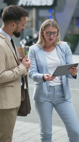 Business professionals engage in a work conversation while using a tablet, showcasing a dynamic exchange of ideas captured in slow motion shots