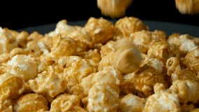 Caramelized sweet popcorn pours and spins, black background, slow motion - Powered by Shutterstock - Get 15% off with code: PIKWIZARD15