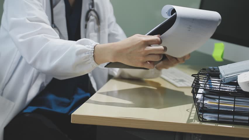 Female Surgeon and Doctor talking at meeting in hospital, They Consult Digital Tablet Computer while Talking about Patient
