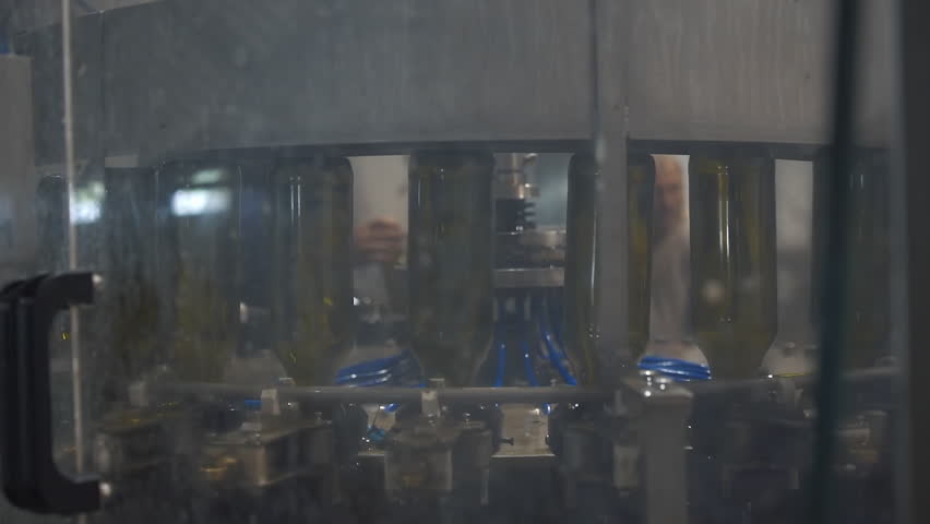 Automated Machine Filling Bottles With Cider Drink. Production Line. Industrial Machine Filling Bottles. Filling Machine At Drinks Manufacturing Factory. Alcoholic Beverages Bottling