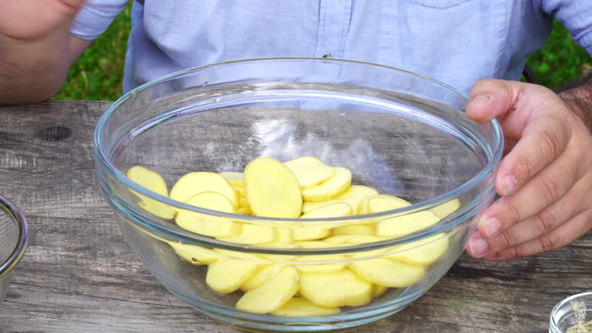 Man marinated potato with seasoning and oil for baking outdoors