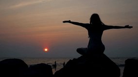 Silhouette serene woman meditating on tranquil sunset ocean beach. Exercise and Healthy lifestyle. A female yogi meditating at beach. Zen Mental health. - Powered by Shutterstock - Get 15% off with code: PIKWIZARD15