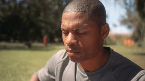 Tired African American athlete wiping sweat from his face while resting outdoors. Exhausted male in fitness clothes taking a break after an intense workout in the park under the sun - Powered by Shutterstock - Get 15% off with code: PIKWIZARD15