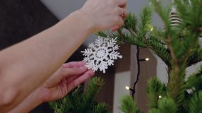 Woman hanging a delicate white snowflake ornament on a beautifully adorned christmas tree, illuminated by warm lights, creates a festive and cozy holiday atmosphere - Powered by Shutterstock - Get 15% off with code: PIKWIZARD15