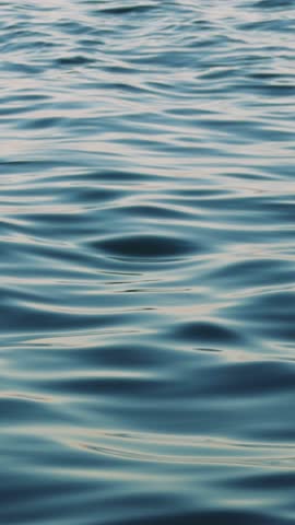 Gentle waves ripple across a deep blue water surface, highlighting nature's beauty and power. The dynamic movement creates a tranquil and serene atmosphere