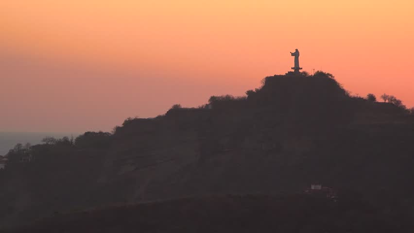 A statue of Jesus on a hill by the ocean during a beautiful sunset in San Juan del Sur