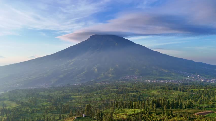 Beautiful rural landscape of Indonesia. Lenticular clouds on the peak of Mount Sumbing, Indonesia. Aerial view of plantation and mountain.