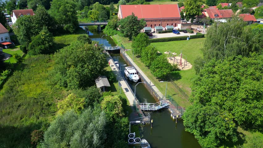 canal lock sluice being used by boats on a sunny summer day in germany Himmelpfort countryside Brandenburg. Perfect aerial view flight drone shot footage from above