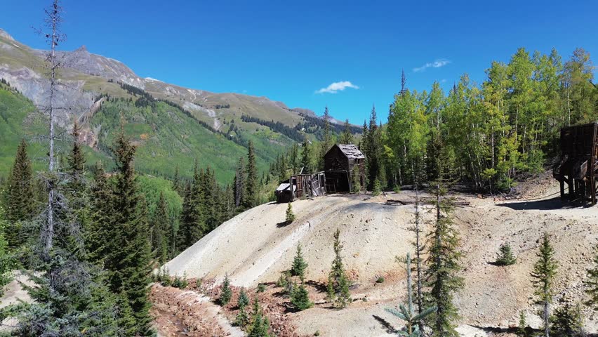 Abandoned unnamed mine site between Ouray and Silverton, Colorado. Flight crosses the site towards a very decayed building then rises over it to reveal the mountains beyond.