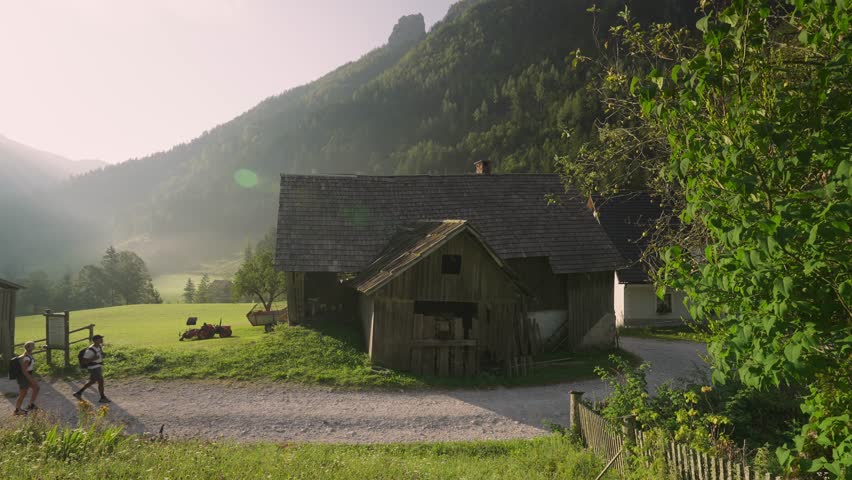 A couple hikes near a rustic farm in Robanov planina valley, Slovenia at sunrise