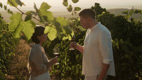 Happy couple drinking wine in vineyards at sunset. Attractive man tasting red wine swirling the glass during grapes harvest season. Travel, dating outdoors in nature, anniversary celebration - Powered by Shutterstock - Get 15% off with code: PIKWIZARD15
