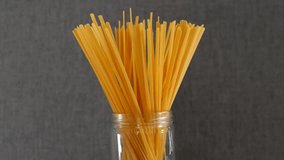 Stick spaghetti pasta uncooked in a jar against grey background, Closeup - Powered by Shutterstock - Get 15% off with code: PIKWIZARD15