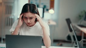 Young asian freelancer woman is massaging her temples, suffering from headache while sitting at the desk and working remotely on a laptop from home - Powered by Shutterstock - Get 15% off with code: PIKWIZARD15