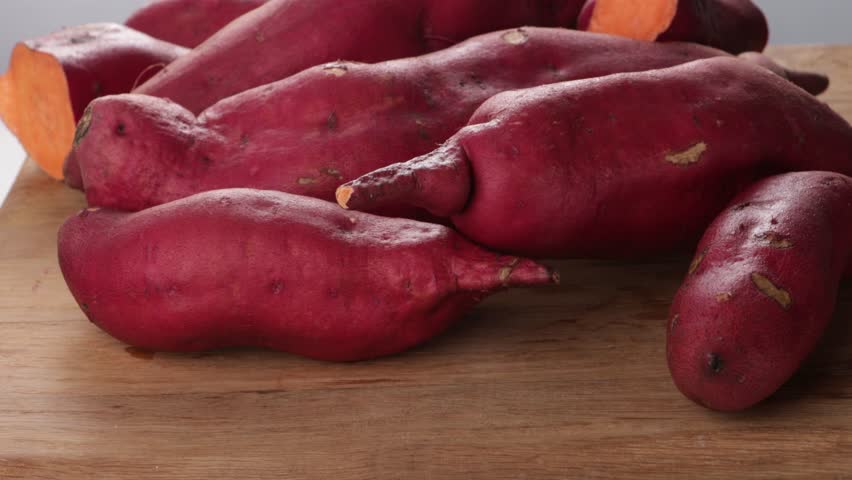 organic fresh sweet potatoes on wooden board