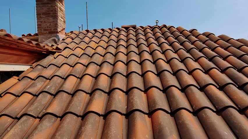 Progress of Residential Roof Tiling on a Sunny Day. Rustic Terracotta Roof Tiles on a Traditional House Under Blue Sky - Powered by Shutterstock - Get 15% off with code: PIKWIZARD15