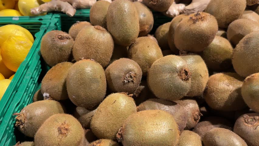Kiwi fruits stacked in a green crate at a market, close-up. High quality 4k footage.