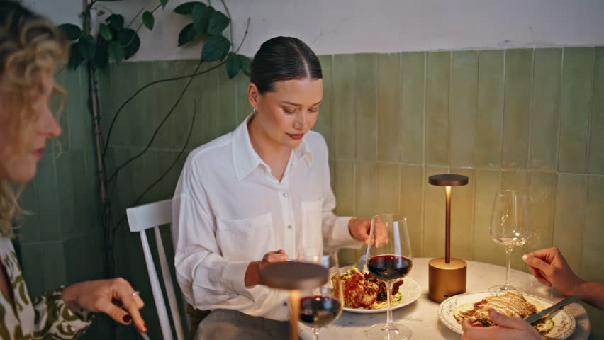 Relaxed three women dining at trendy restaurant engaged in conversation. Happy ladies talking together enjoy gourmet dishes closeup. Happy female friends laughing spending evening in friendly hangout.