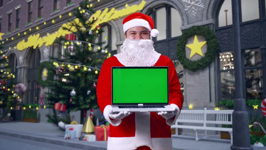 Asian Santa Claus Showing Green Screen Laptop While Standing In Christmas Night - Powered by Shutterstock - Get 15% off with code: PIKWIZARD15