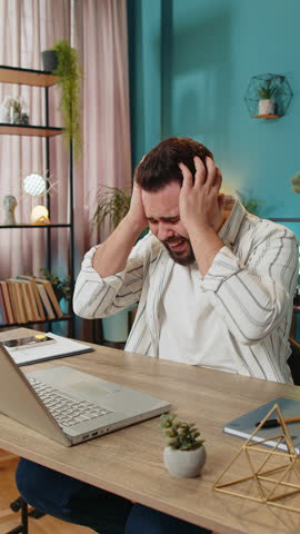Displeased sad business man using laptop notebook typing browsing working loses becoming surprised sudden lottery results bad news fortune loss game fail computer virus. Guy at home office. Vertical