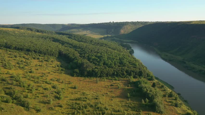 Drone footage of a majestic river flowing through hilly terrain. Location place Dniester Canyon, Ukraine, Europe. Cinematic aerial shot. Filmed in UHD 4k video. Discover the beauty of earth.