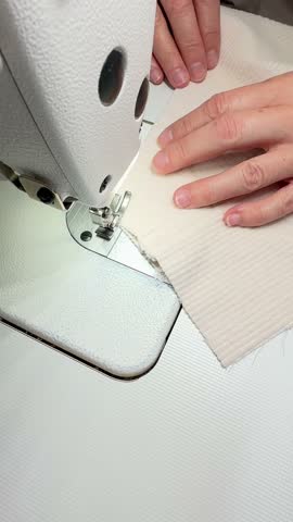 A female seamstress sews a skirt, trousers made of white corduroy, velour, a fashion expert, a fashion factory or studio, an atelier, a vision of a design startup. Vertical video. 3D Illustration