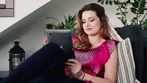 Young woman with tablet computer on sofa, steadicam shot
