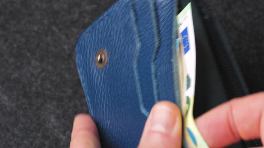 A closeup view of cash being stored in a blue wallet for financial purposes