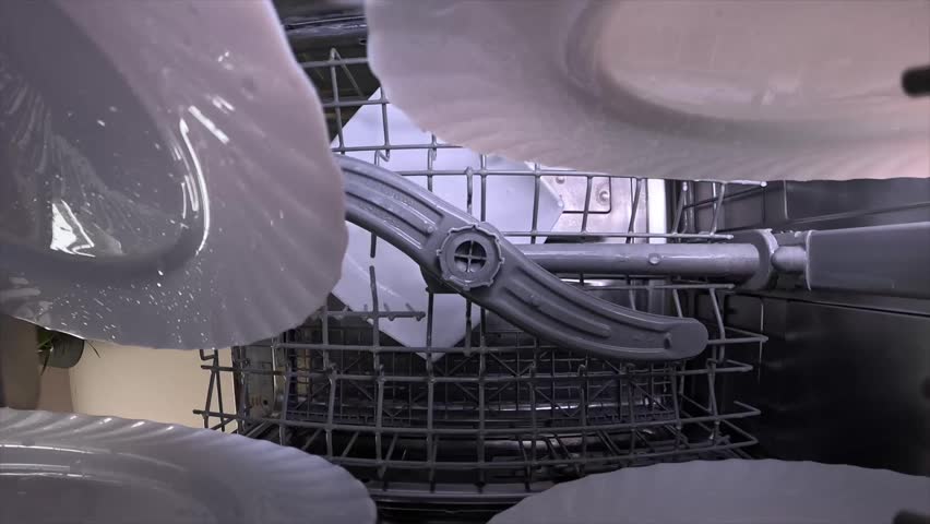 view from inside the working dishwasher. Water splashes clean dirty dishes