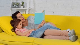 mother reading aloud book near happy daughter - Powered by Shutterstock - Get 15% off with code: PIKWIZARD15