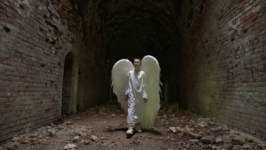 Man in angel costume walks through tunnel. Faith and religion concept.