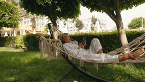 girl resting on a hammock with a tablet in hand on a forest background. High quality 4k footage - Powered by Shutterstock - Get 15% off with code: PIKWIZARD15
