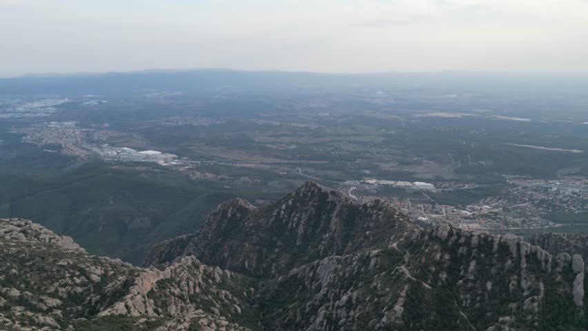 Aerial view of a majestic mountain range overlooking a picturesque valley and town below