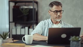 Smiling businessman typing on laptop computer in home office. Happy mid adult professional man working. Modern entrepreneur or freelancer using digital technology for telecommuting, staying connected. - Powered by Shutterstock - Get 15% off with code: PIKWIZARD15