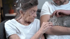 Animal therapy. An elderly person and caregiver receiving psychological support using pets in a nursing home. The senior woman is very happy and strokes a cute kitten with an assistant on the couch. - Powered by Shutterstock - Get 15% off with code: PIKWIZARD15