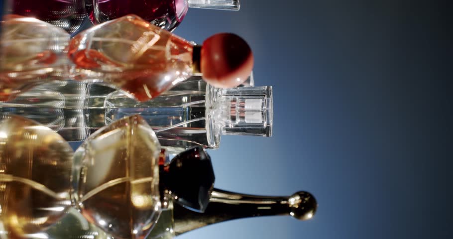 A collection of assorted perfume bottles with elegant design and reflective surfaces. The image captures colorful glass containers in a luxurious setting, conveying a sense of opulence and refinement.