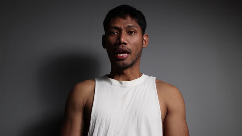 Angry young man pointing finger accusingly. Angry young adult male is pointing his finger aggressively at the viewer while shouting.