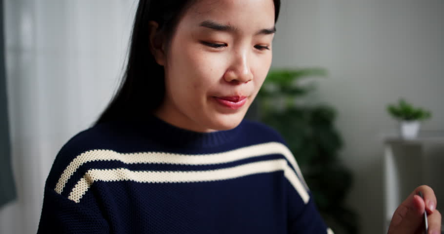 Handheld selective focus shot, Happy Asian woman eating salad in the morning at the table in the living room. Healthy food, Eating and drinking concept.