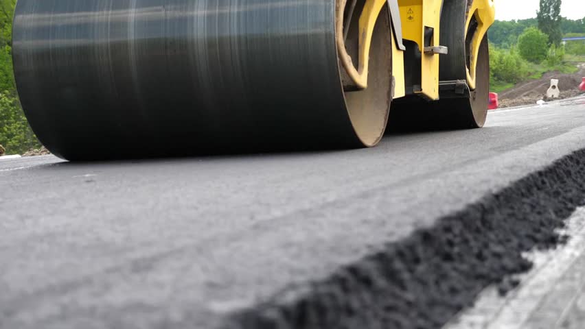 Roller laying new asphalt layer. Special machinery making road. Compactor constructing highway. Steamroller slowly ride. Roadway repair by heavy machinery. Concept of roadwork and motorway maintenance