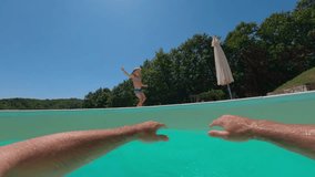A laughing happy little boy jumps into his daddy's arms and has fun in the swimming pool on a sunny day. POV view - Powered by Shutterstock - Get 15% off with code: PIKWIZARD15