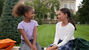 Smiling schoolgirls classmates female friends little girls children kids school education outdoors talk chat friendly conversation multiethnic happy African Indian teen sisters students study outside - Powered by Shutterstock - Get 15% off with code: PIKWIZARD15