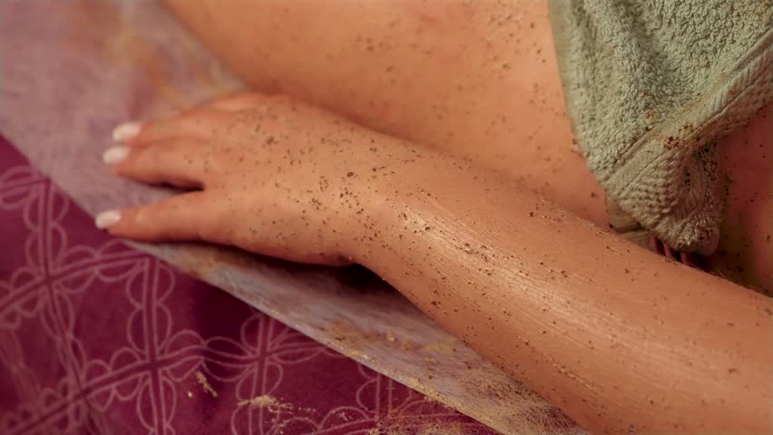 Scrub for face and body with abrasive particles brown color on hand of woman client. Exfoliating cosmetic gommage. Peeling and scrubbing female hand with natural coffee scrub