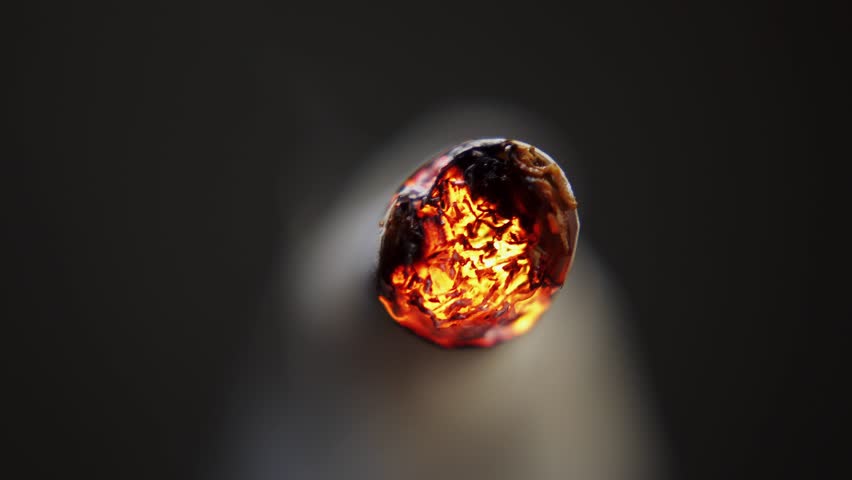 Macro video of a burning cigarette. Ignition and smoke from a lit cigarette. Smoking is harmful to health
