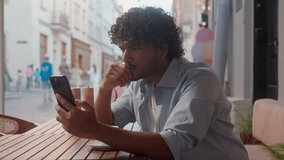 Sad thoughtful Indian Arabian man guy male businessman student tourist in cafe drink coffee read message bad news mobile phone gadget addict confused upset think problem cellphone using outdoors city - Powered by Shutterstock - Get 15% off with code: PIKWIZARD15